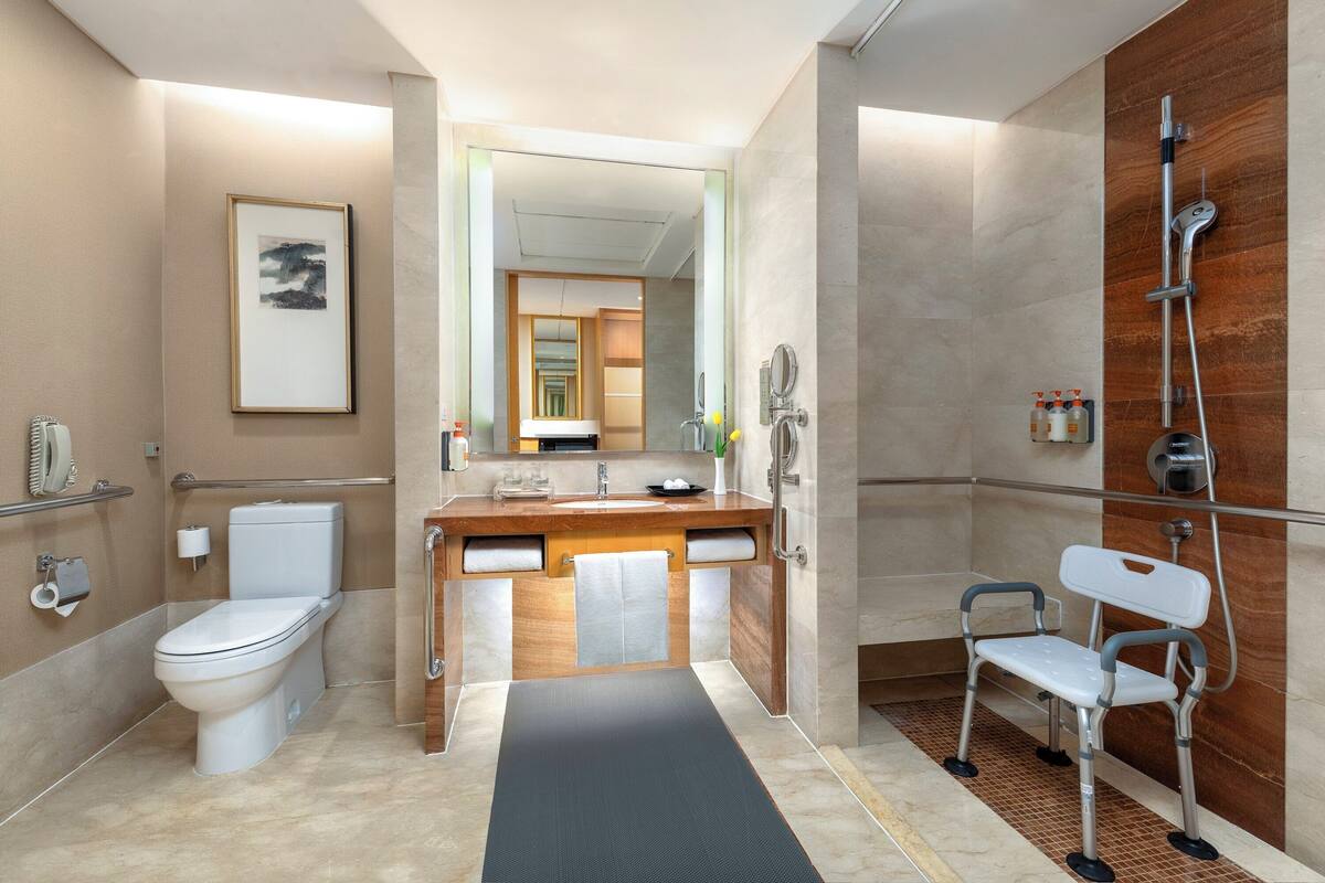 Un baño moderno con inodoro, lavamanos, espejo y ducha.