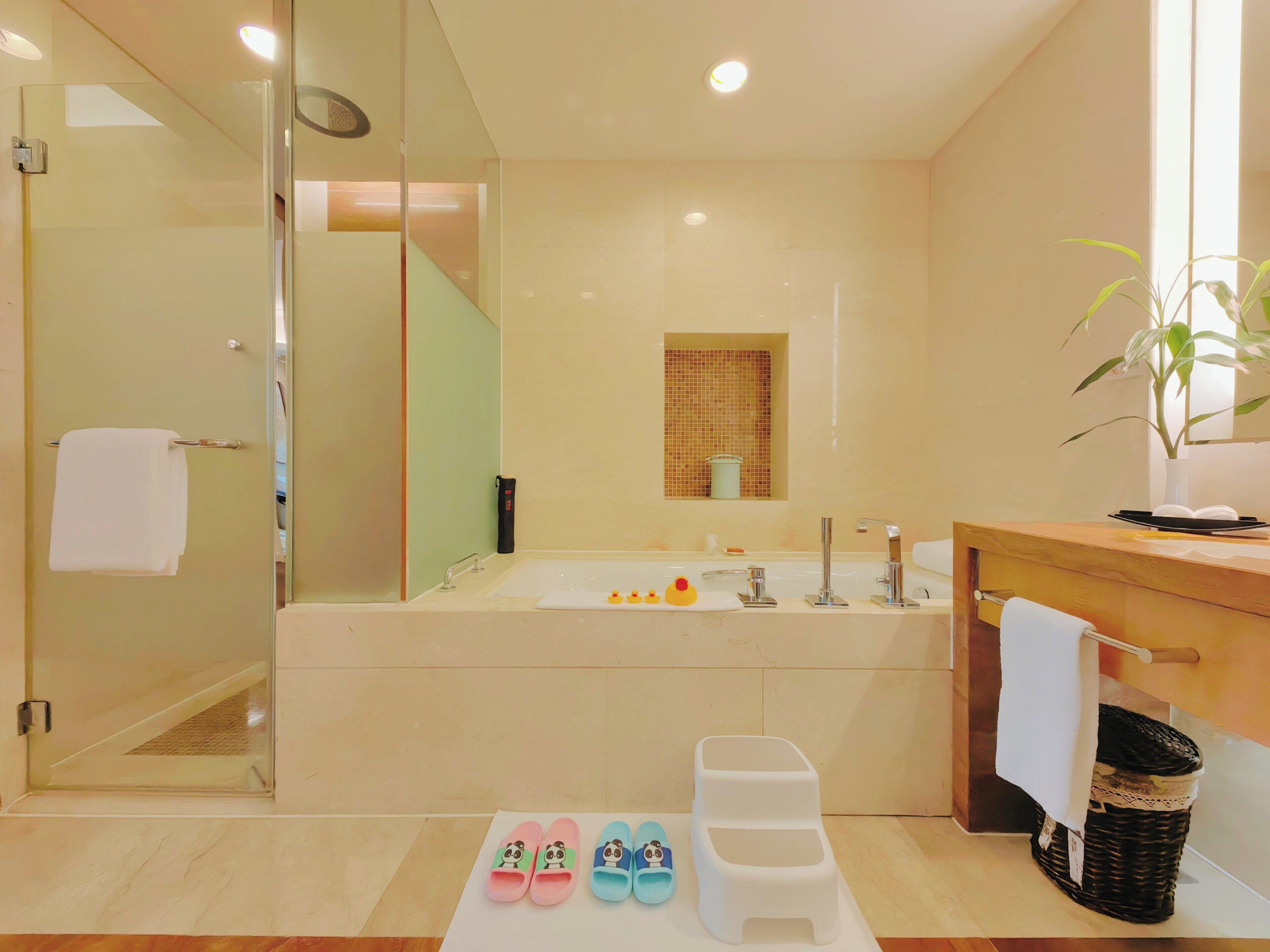 Ein modernes Badezimmer mit Duschkabine aus Glas, einer großzügigen Badewanne und einem Holzbadezimmer-Möbel mit Spiegel.