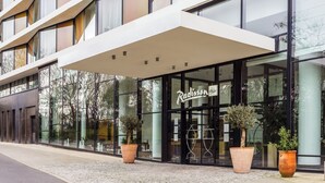 A modern building with large glass windows and a sign reading "Radisson". There are large potted plants in front of the entrance. - Radisson Blu Hotel, Montpellier (Montpellier)