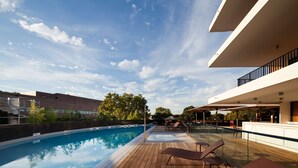 A rooftop pool with wooden deck, lounge chairs, and a modern building in the background. - Radisson Blu Hotel, Montpellier (Montpellier)