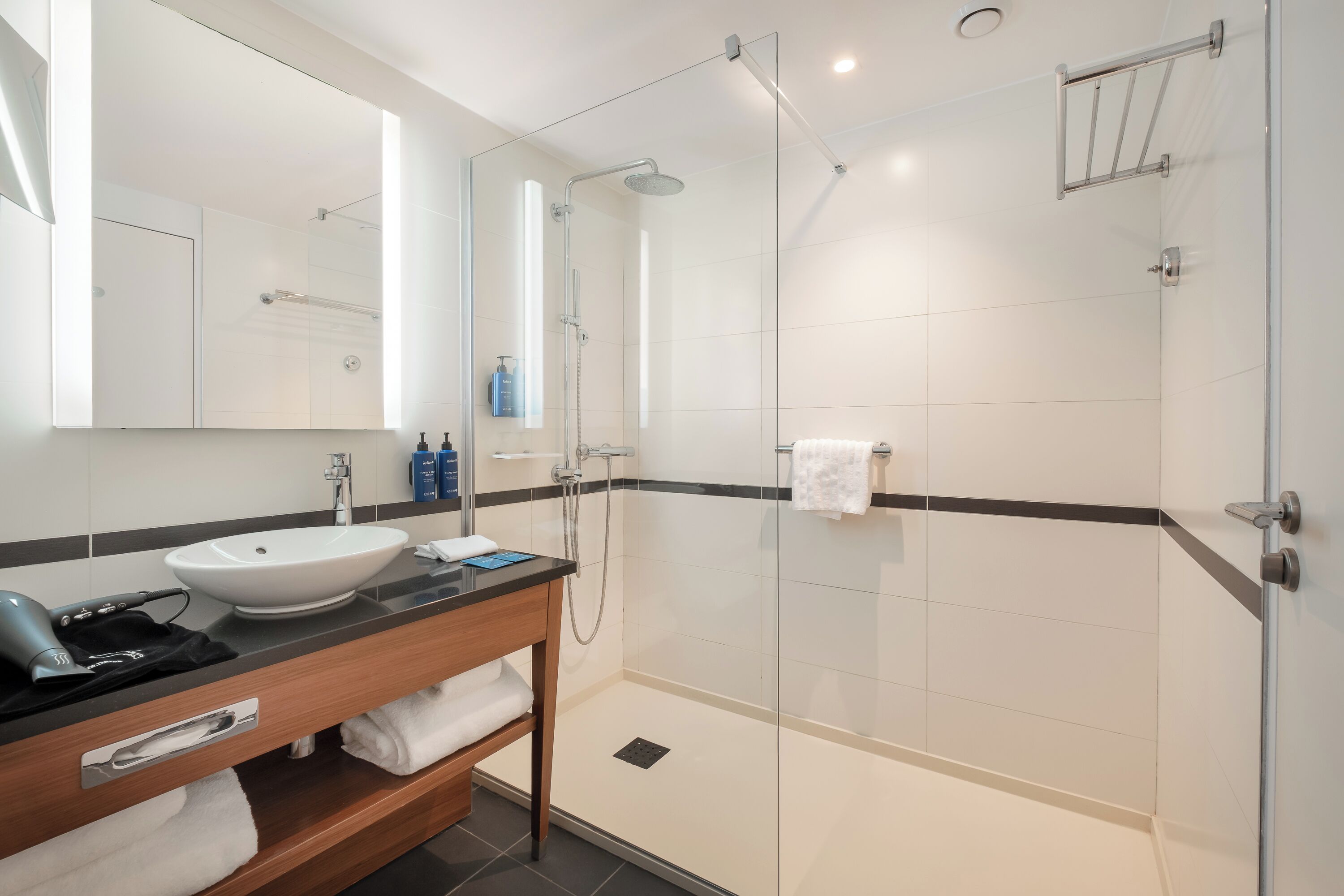 Une salle de bain moderne avec une douche à parois de verre, un lavabo blanc et un meuble-lavabo avec un miroir.