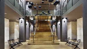 A modern hotel lobby with a central staircase, glass railings, and black metal chairs. - Holiday Inn Tbilisi by IHG (Tbilisi)