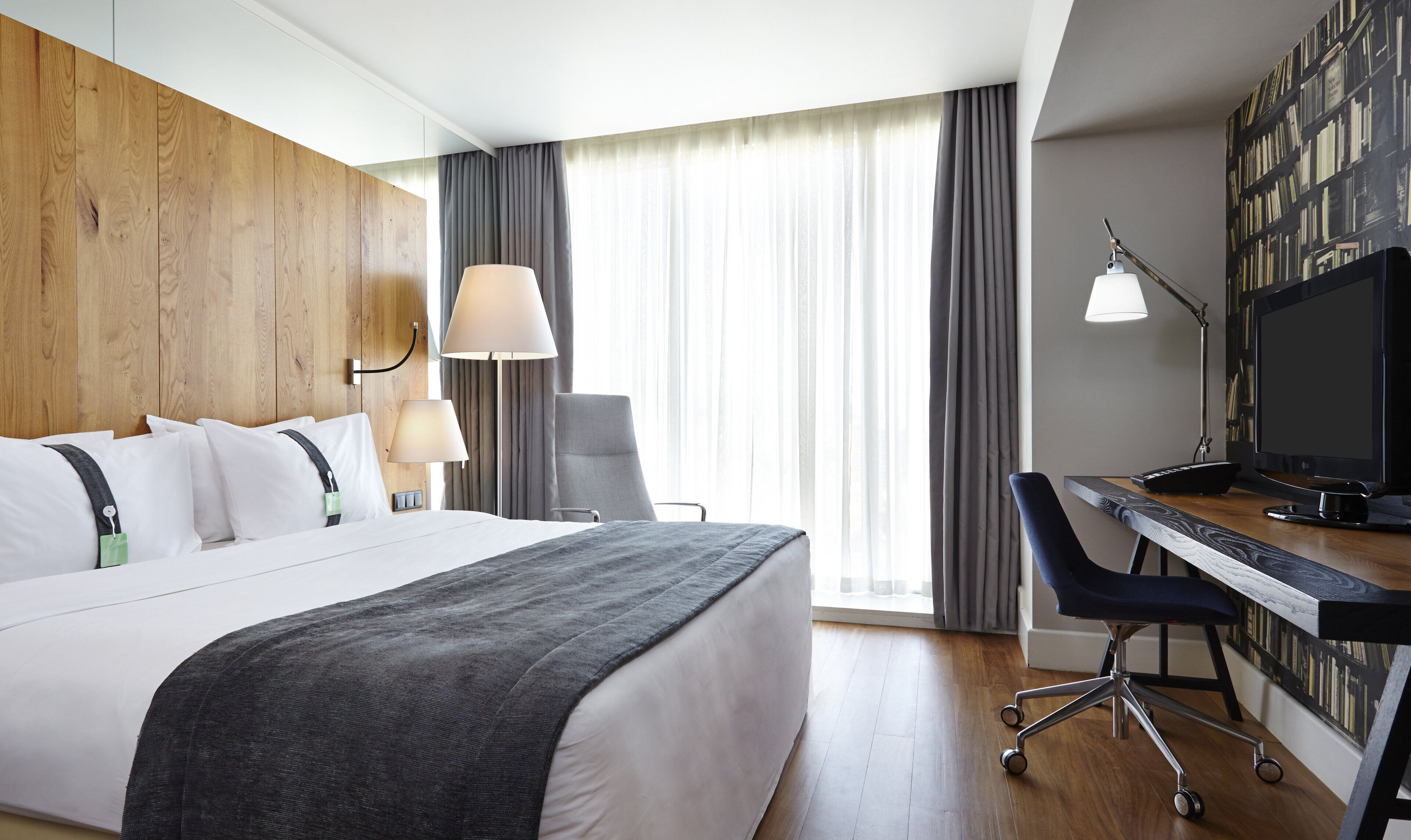 Una habitación de hotel con una cama, escritorio, silla y televisor.