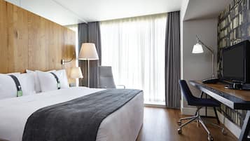 Una habitación de hotel con una cama, escritorio, silla y televisor.