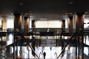 A spacious lobby with a central staircase, glass railings, and seating areas. - Holiday Inn Tbilisi by IHG (Tbilisi)