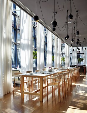A modern dining area with long tables, chairs, and pendant lighting. - Holiday Inn Tbilisi by IHG (Tbilisi)
