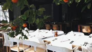 Un restaurante con manteles blancos, sillas de madera y un naranjo colgante.
