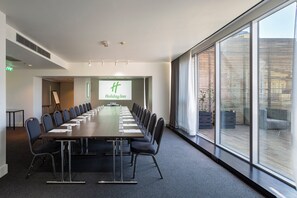 A conference room with a long table, chairs, and a projection screen displaying 'Holiday Inn'. - Holiday Inn Tbilisi by IHG (Tbilisi)