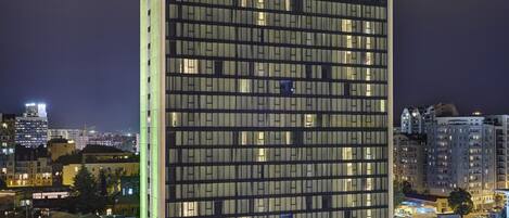 A Holiday Inn hotel with a modern glass facade, multiple floors, and a parking area in front.