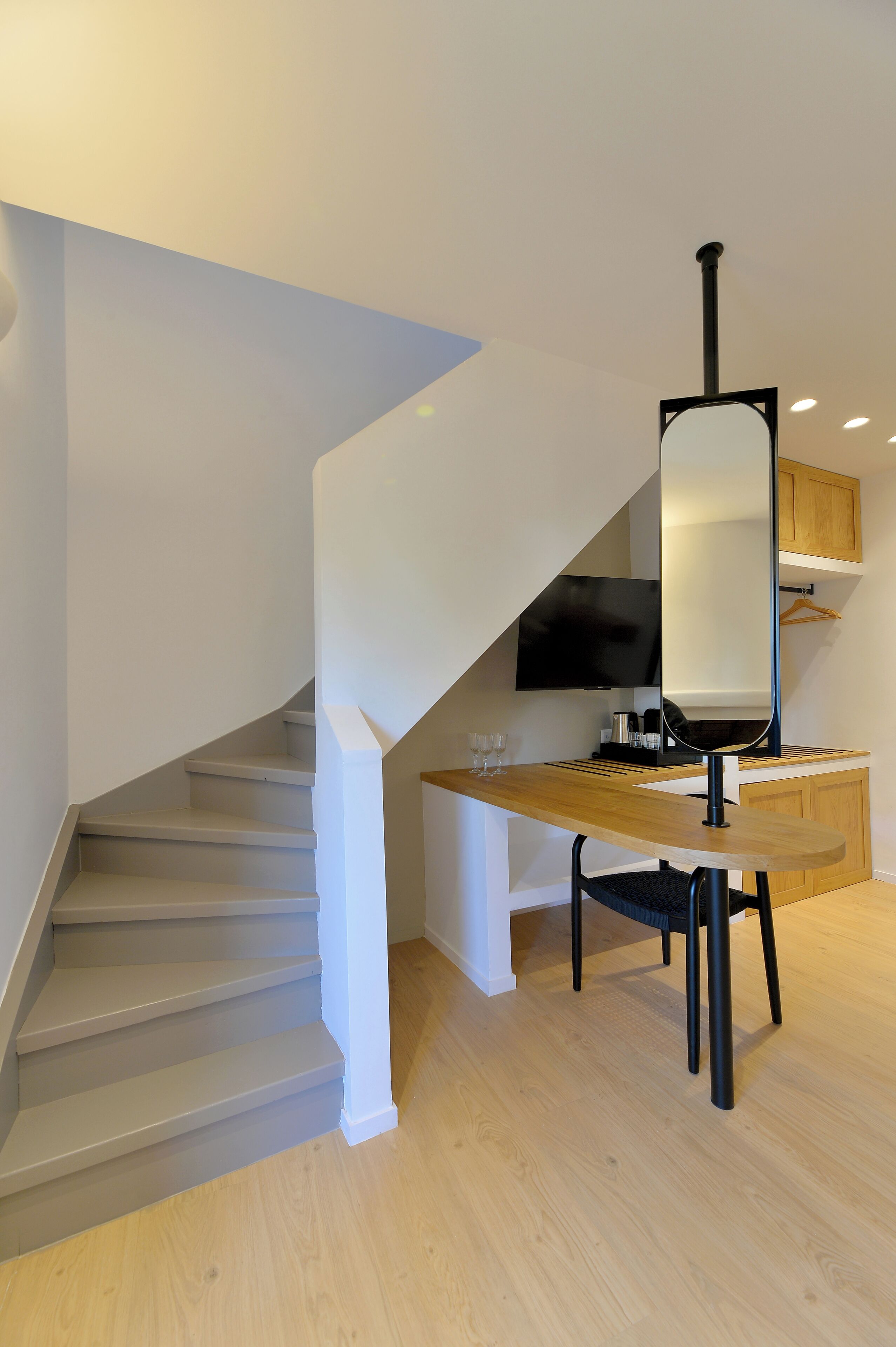 Una cocina moderna con encimera de madera, una silla negra y un televisor montado en la pared.
