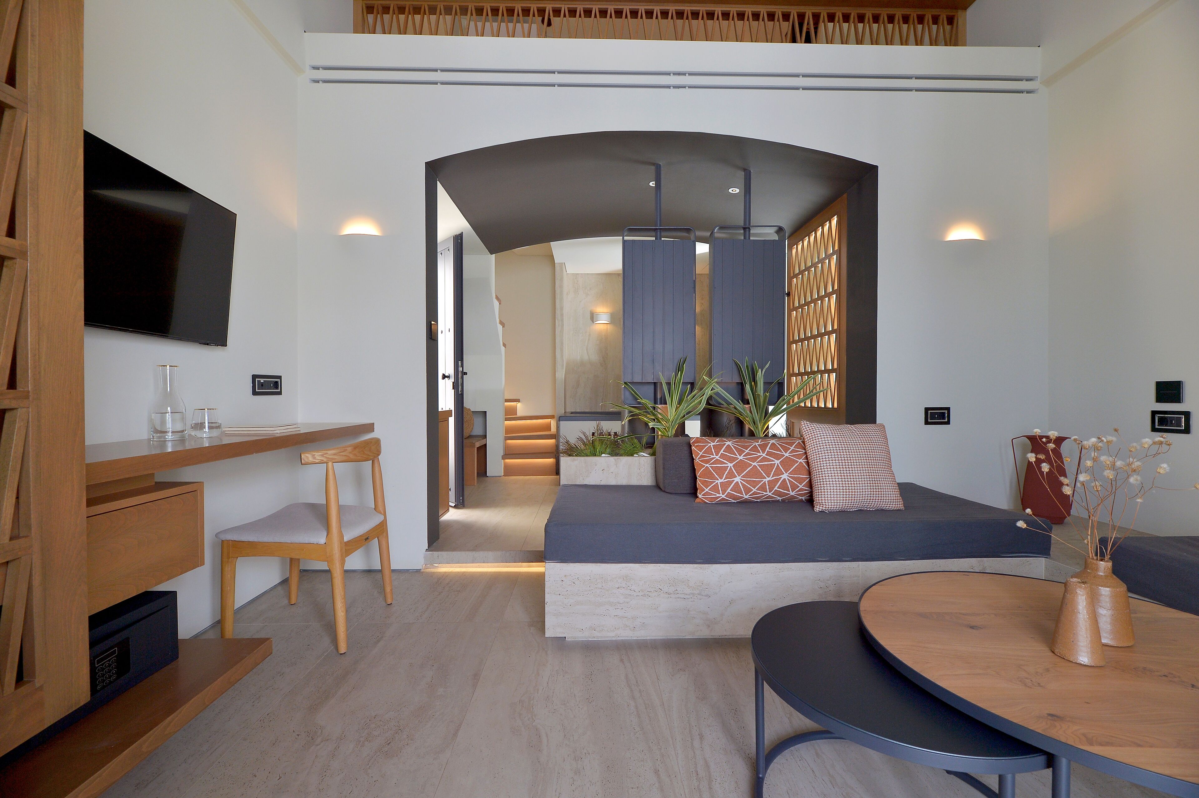 Een moderne woonkamer met een bank, een eettafel en een aan de muur bevestigde televisie.