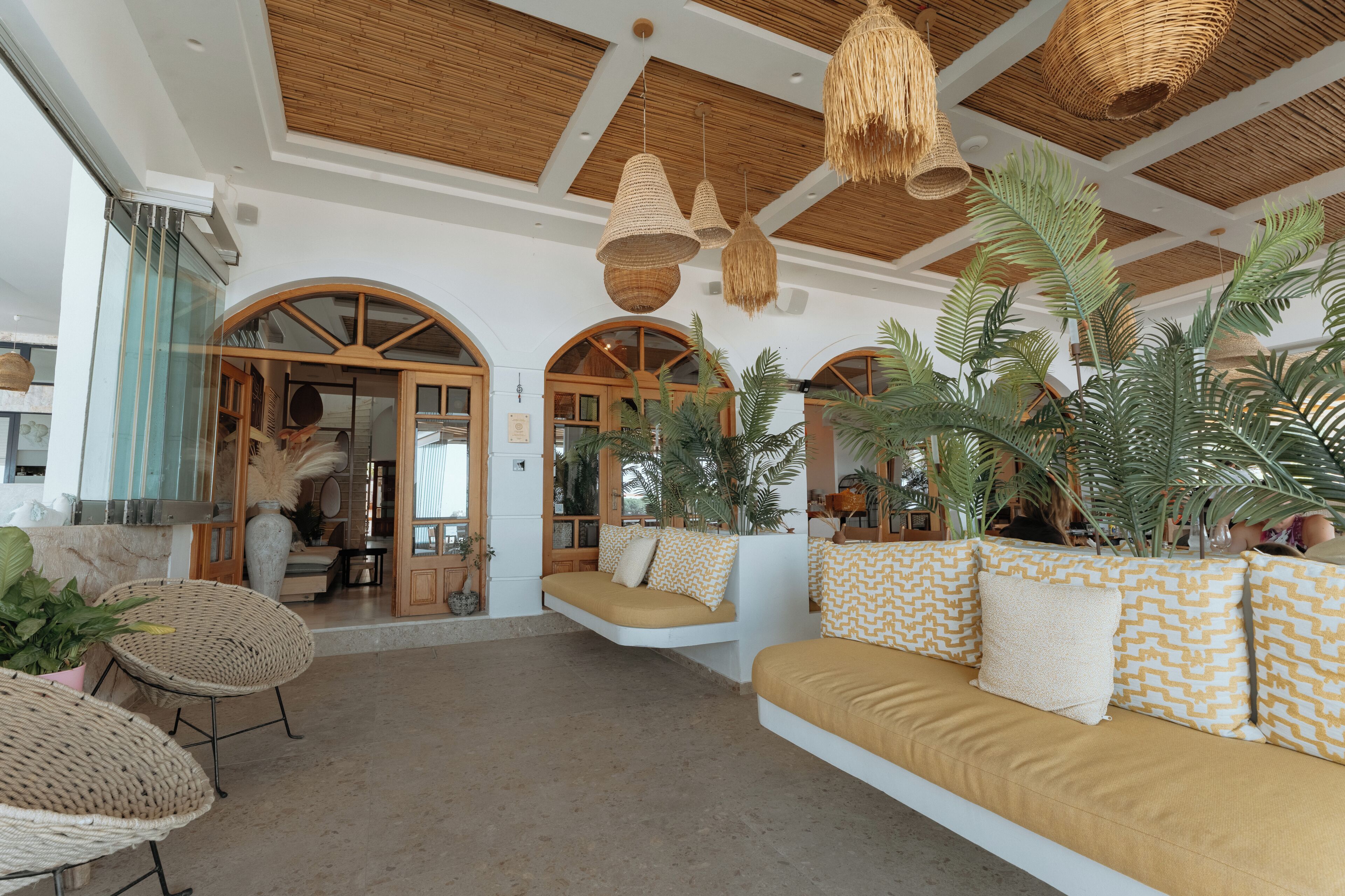 A spacious interior with a high ceiling, woven ceiling lamps, and a seating area with cushions.