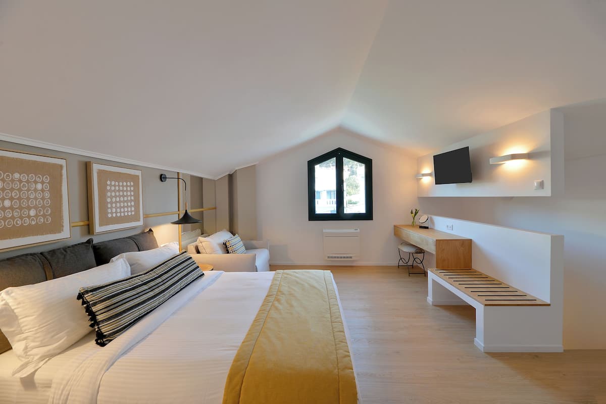 Une chambre moderne avec un grand lit, un bureau et un téléviseur fixé au mur.