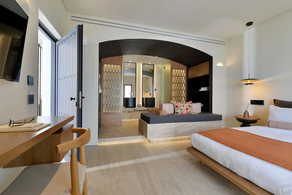 Une chambre d’hôtel moderne dotée d’un grand lit, d’un bureau et d’un coin salon.