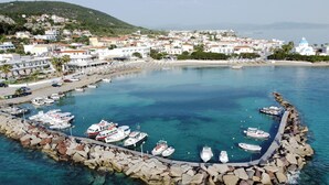 A coastal town with a marina, rocky breakwater, and buildings with white and blue domes.