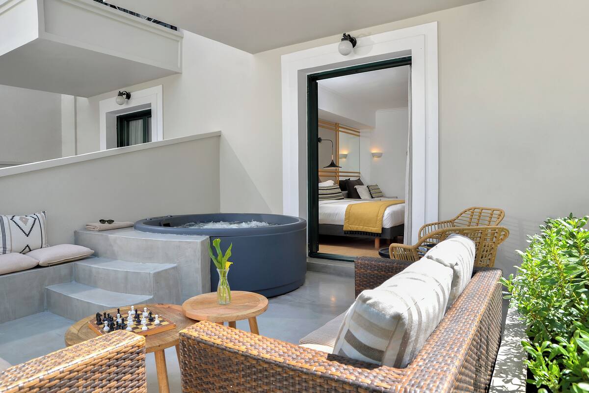 Un espace de vie moderne doté d’un jacuzzi, d’un coin salon extérieur et offrant une vue sur une chambre.