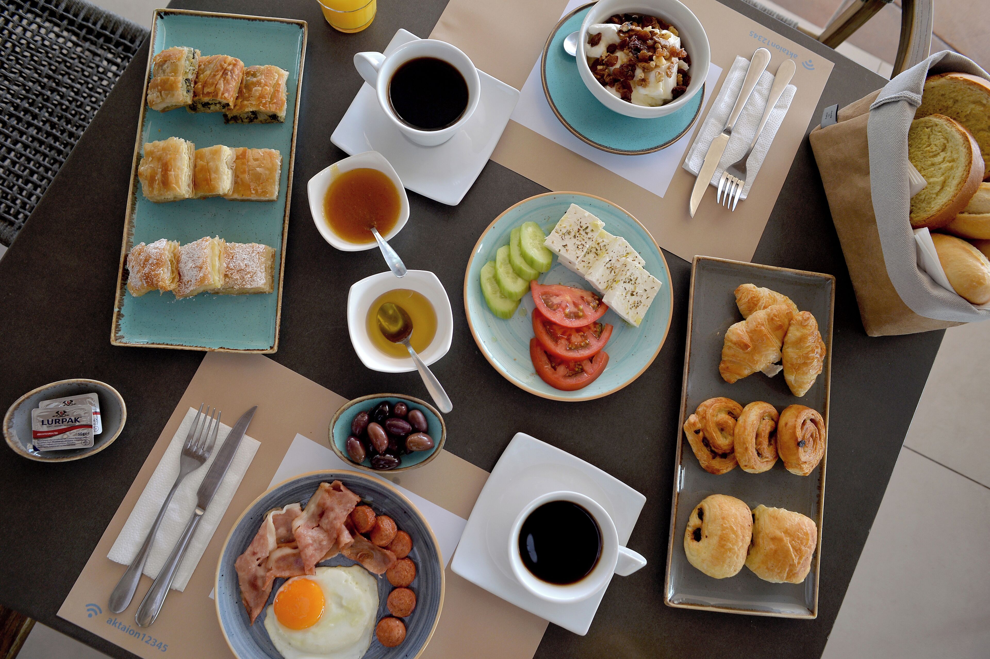 A breakfast table with various food items, including pastries, eggs, and coffee.