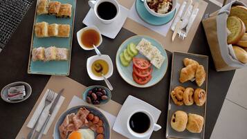 A breakfast table with various food items, including pastries, eggs, and coffee.