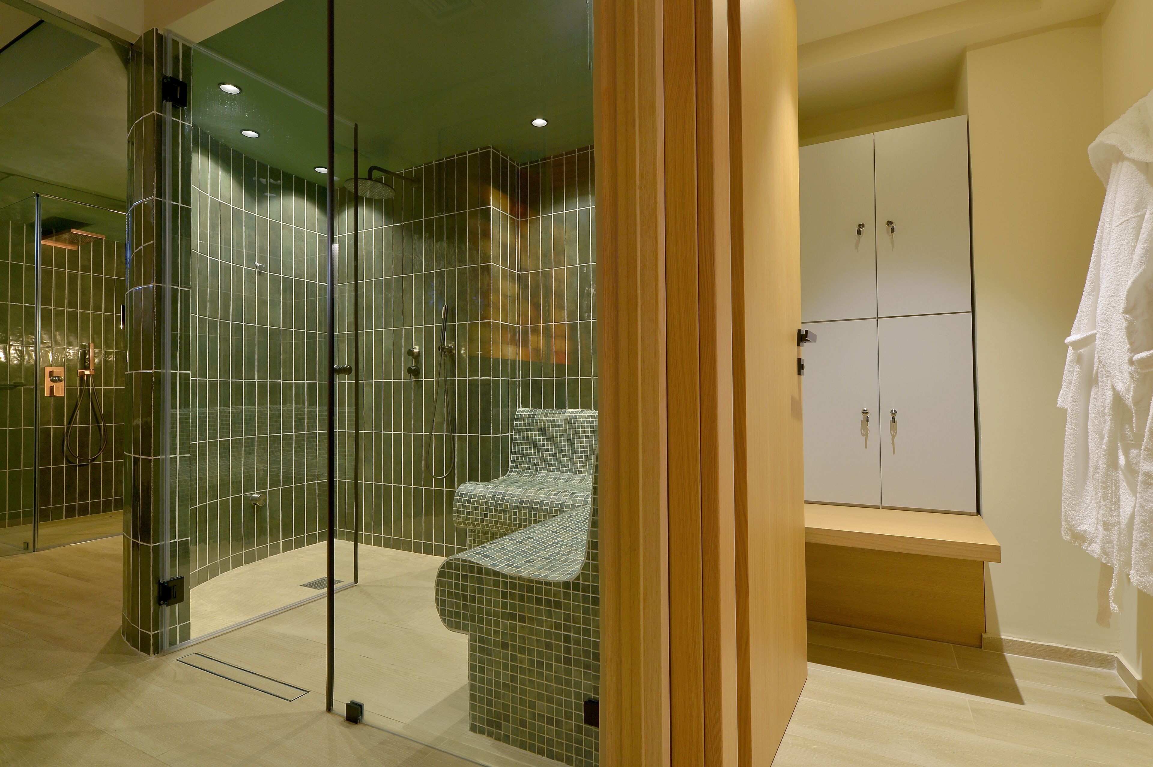 Un bagno moderno con doccia vetrata, una panca e un mobile vanitario in legno con pensili.