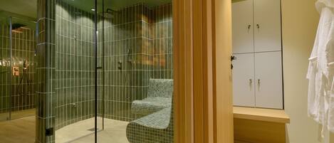 A modern bathroom with a glass-enclosed shower, a bench, and a wooden vanity with cabinets.