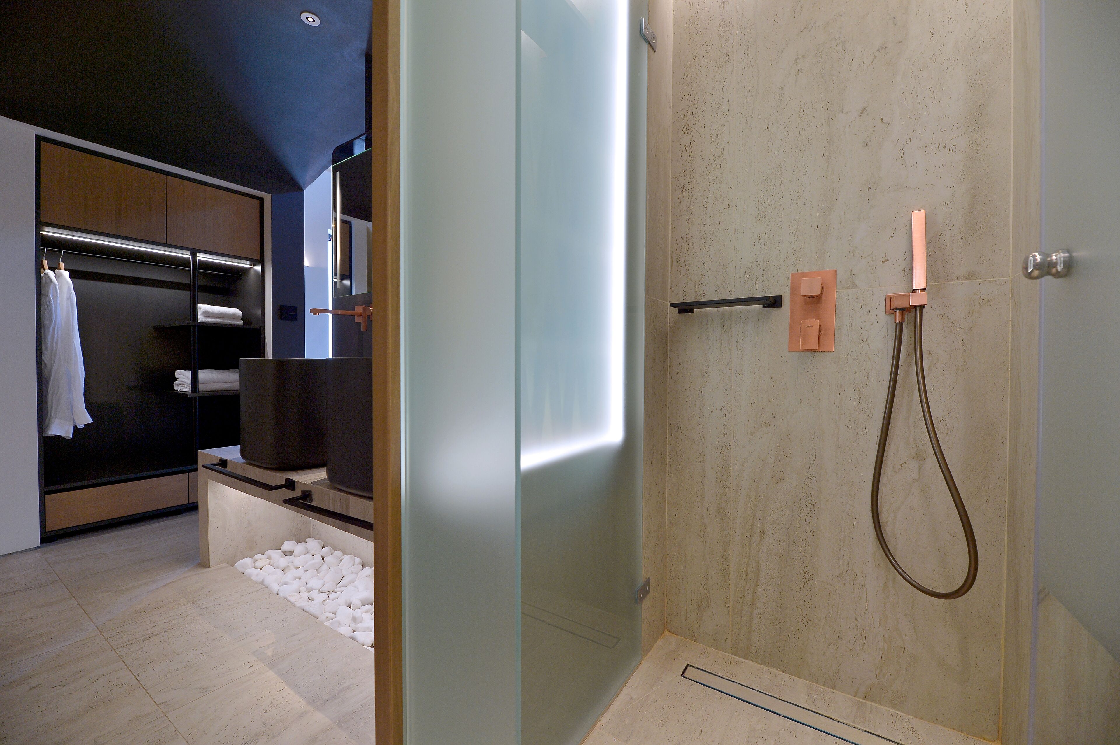 A modern bathroom with a glass shower enclosure, a built-in towel rack, and a wooden vanity.