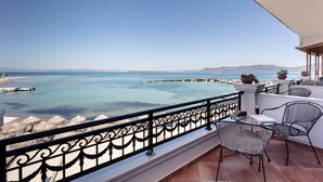 A balcony with a view of the sea, a table with chairs, and a railing.
