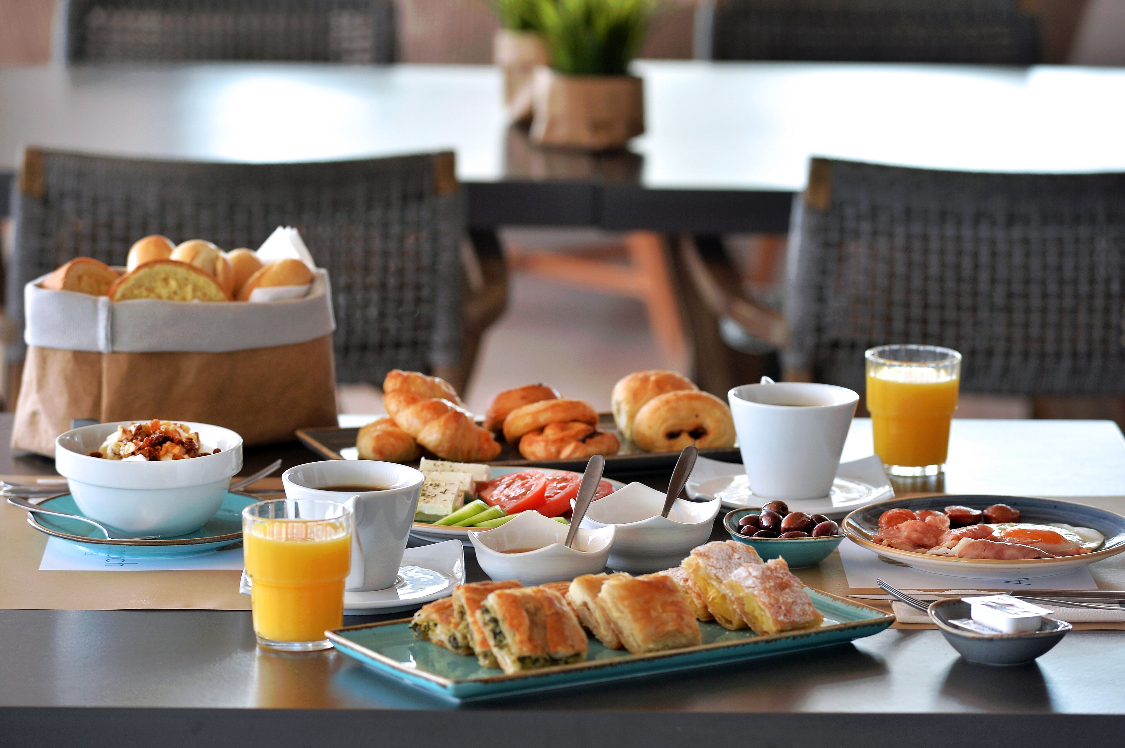 Una mesa de desayuno con cruasanes, pastelería y una variedad de frutas y verduras.