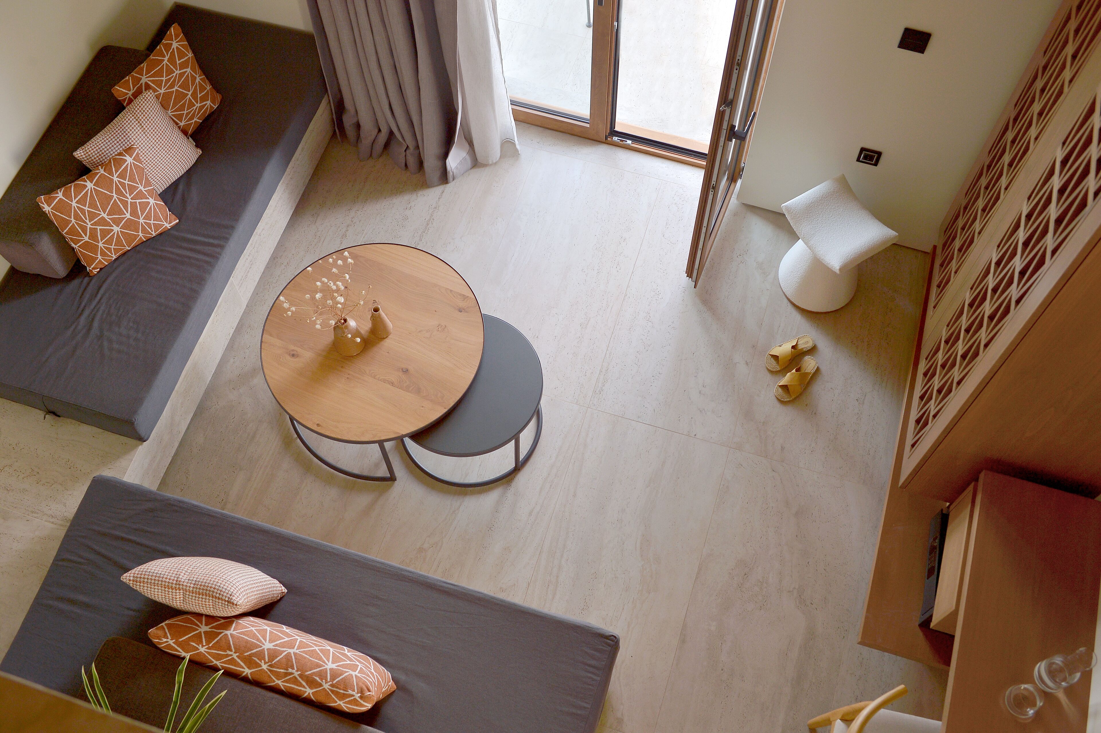 A modern living room with a sofa, a round wooden table, and a small white stool.