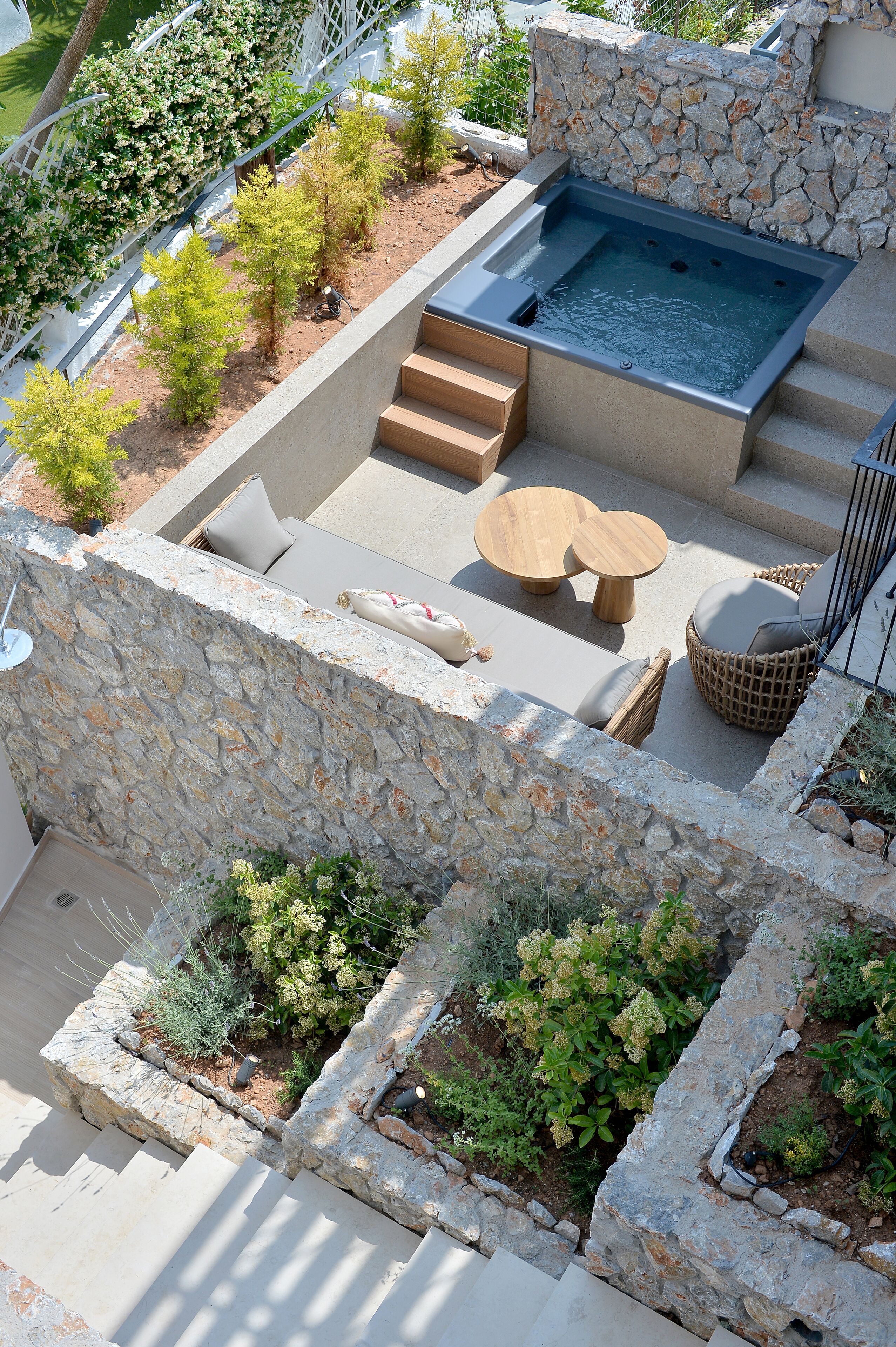 Une terrasse sur le toit avec un jacuzzi, des sièges d’extérieur et des jardinières en pierre.