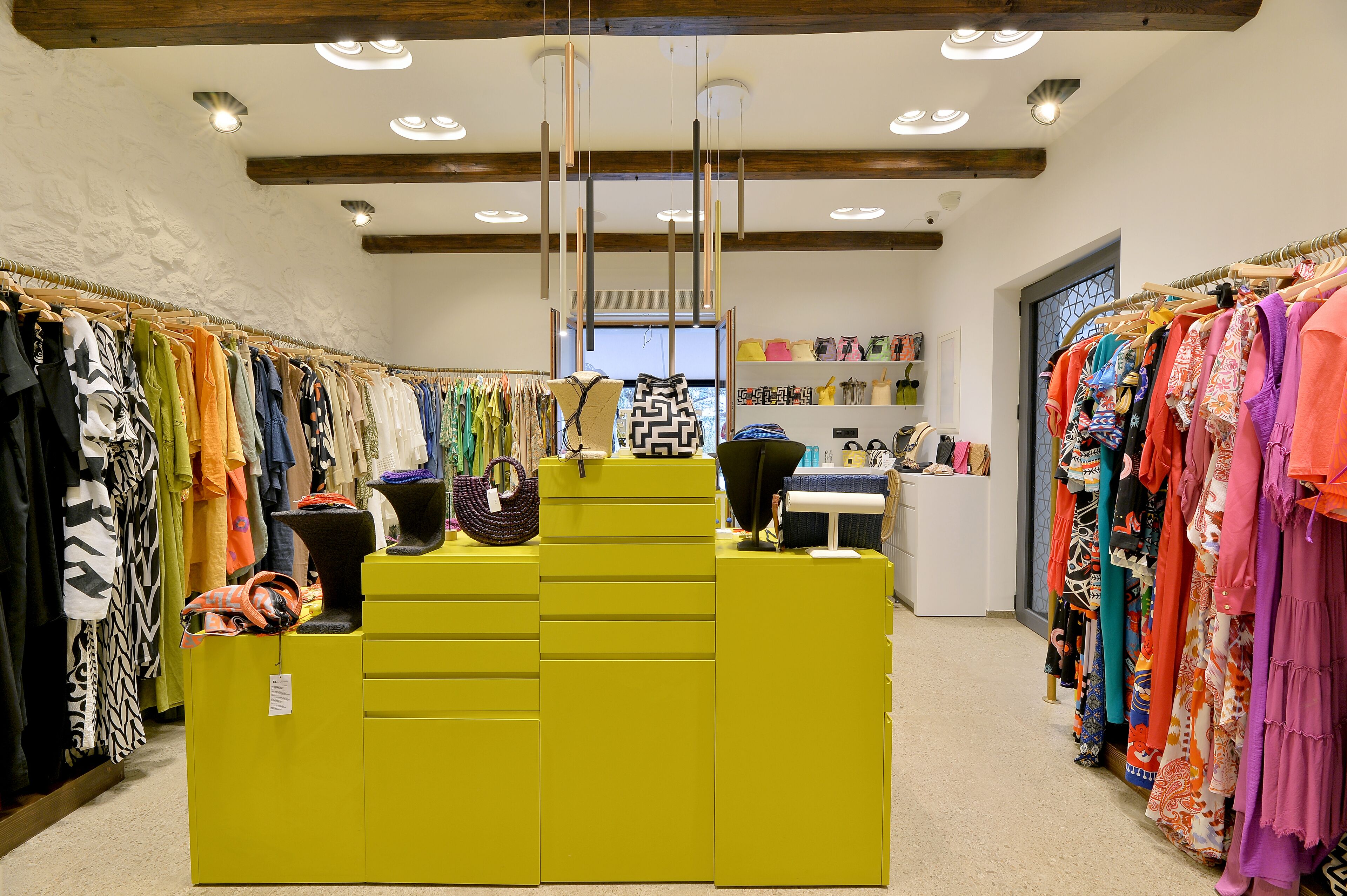 A clothing store with a bright yellow counter and various garments on racks.