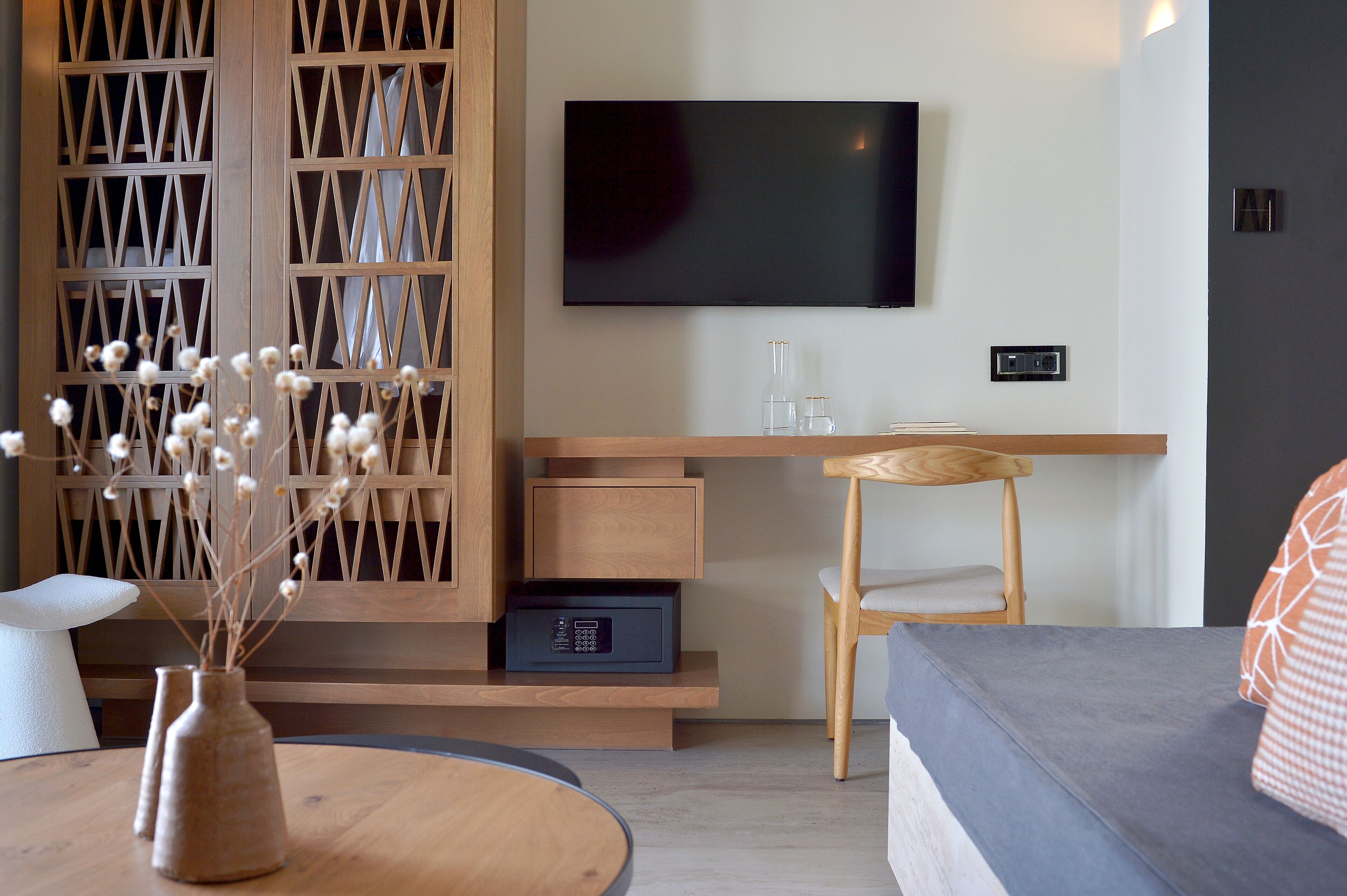 Ein modernes Wohnzimmer mit einem an der Wand montierten Flachbildfernseher, einem Holztisch mit Stuhl und einem Sofa.