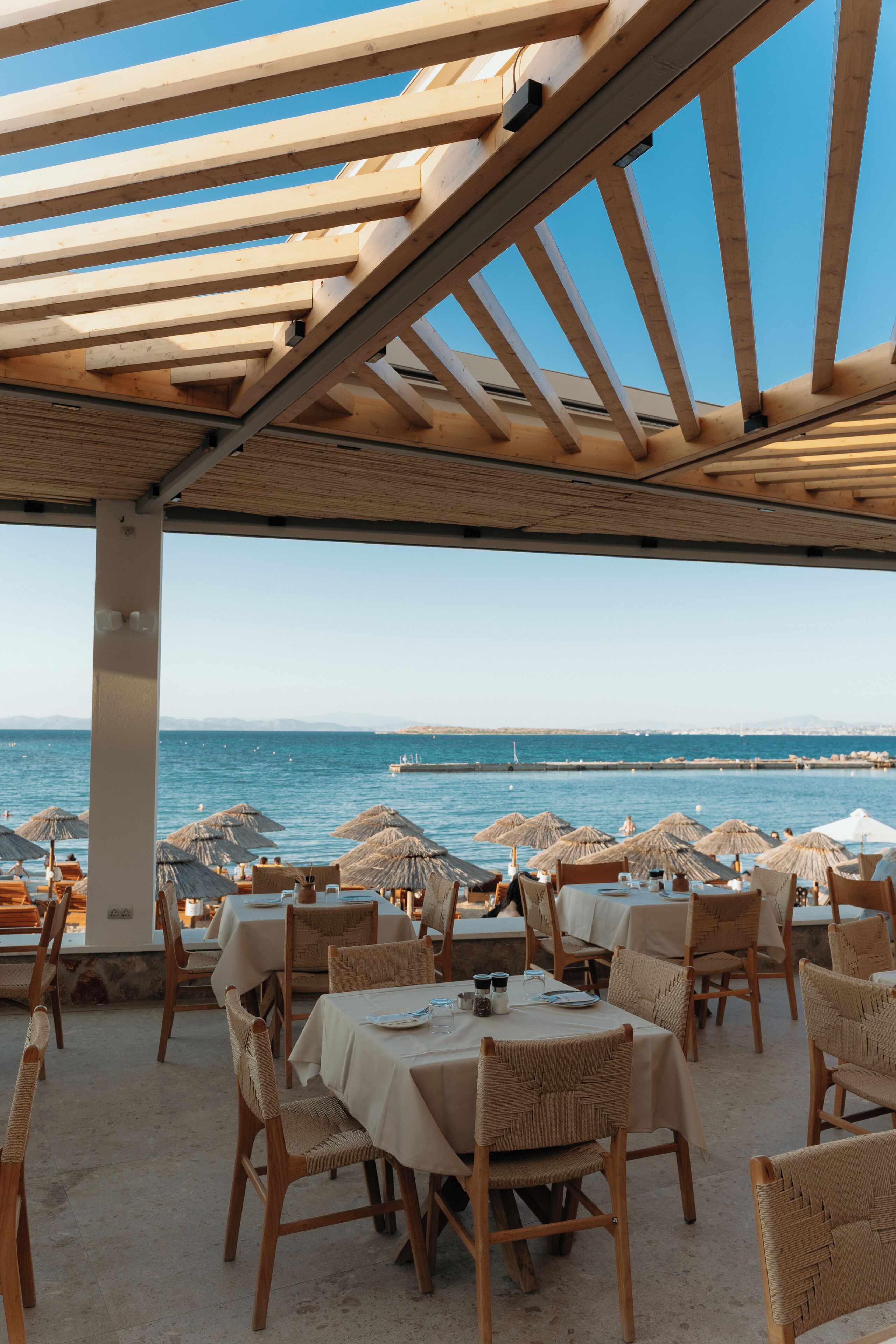 An outdoor dining area with tables and chairs, overlooking a body of water.