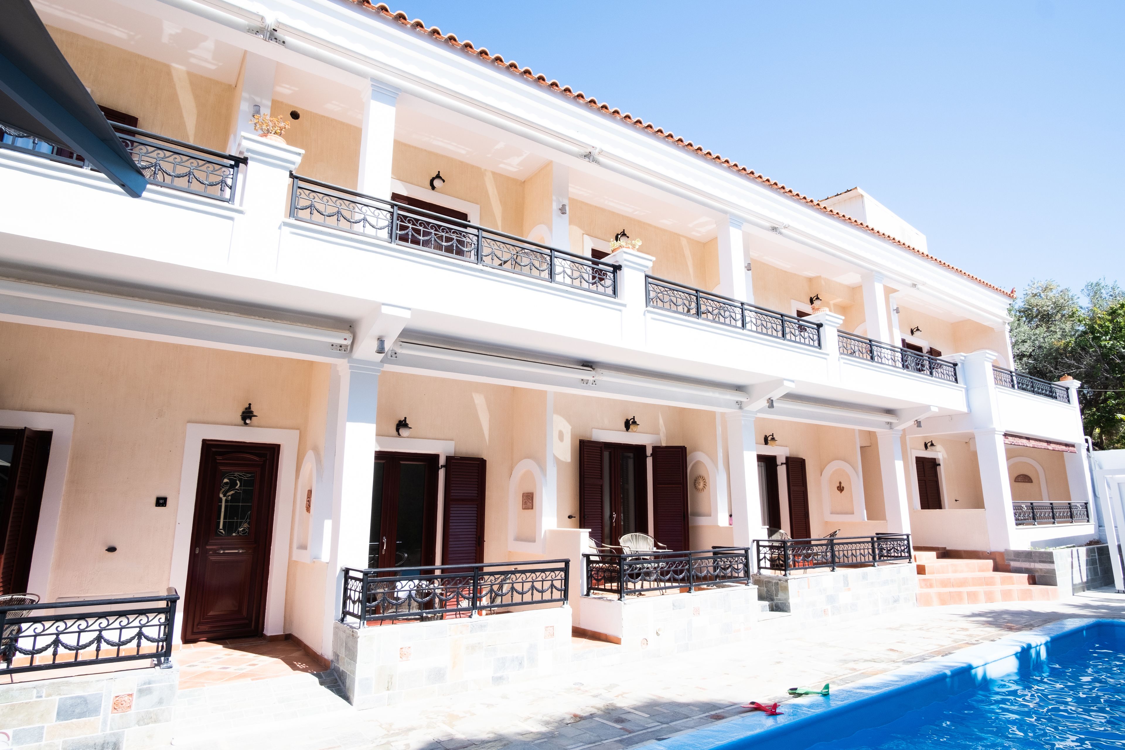 Un edificio de dos pisos con piscina, balcones y un espacio exterior cubierto.