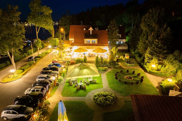 A hotel with a parking lot, outdoor seating area, and well-maintained gardens.