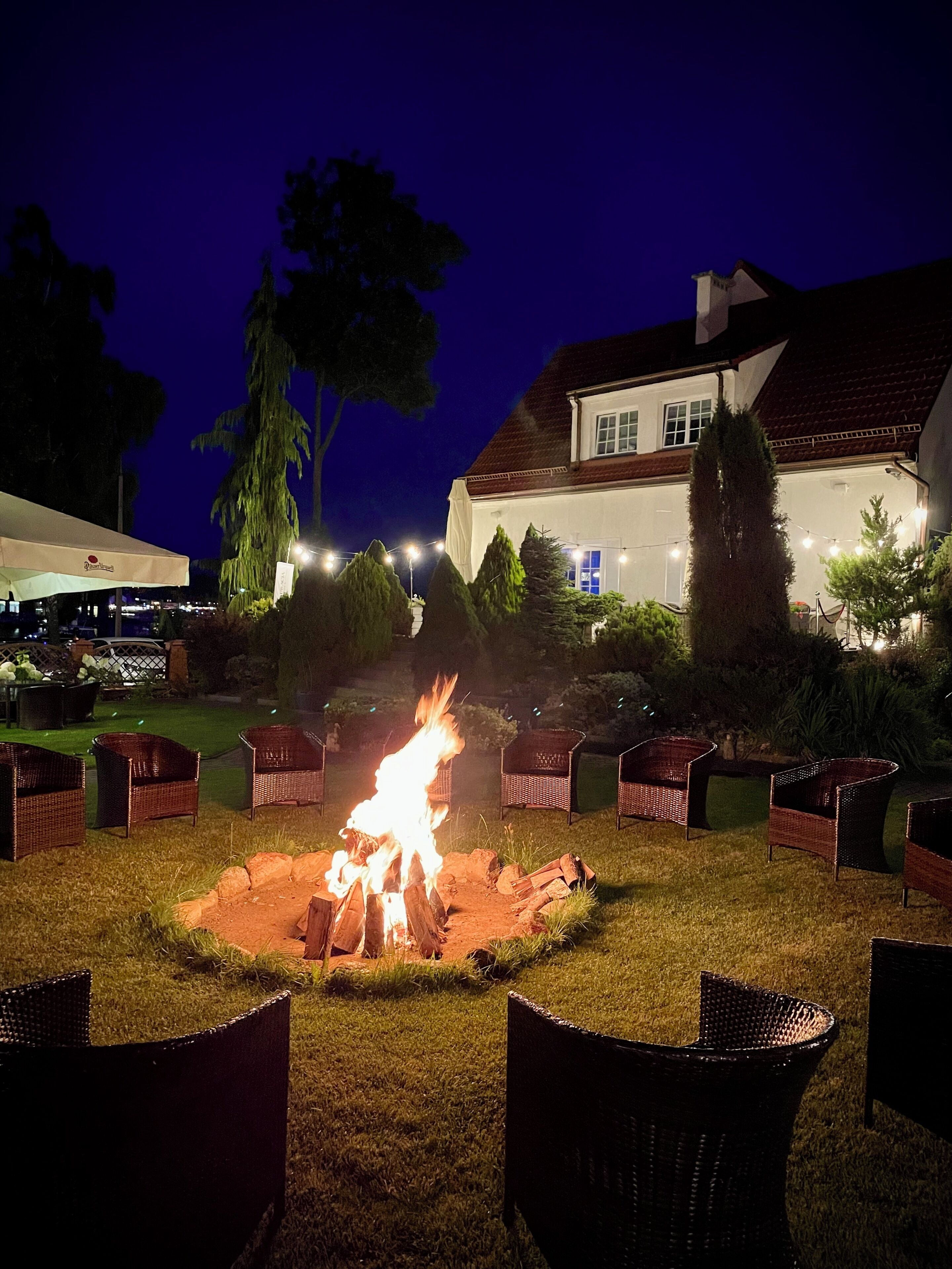 An outdoor seating area with wicker chairs arranged around a central fire pit.