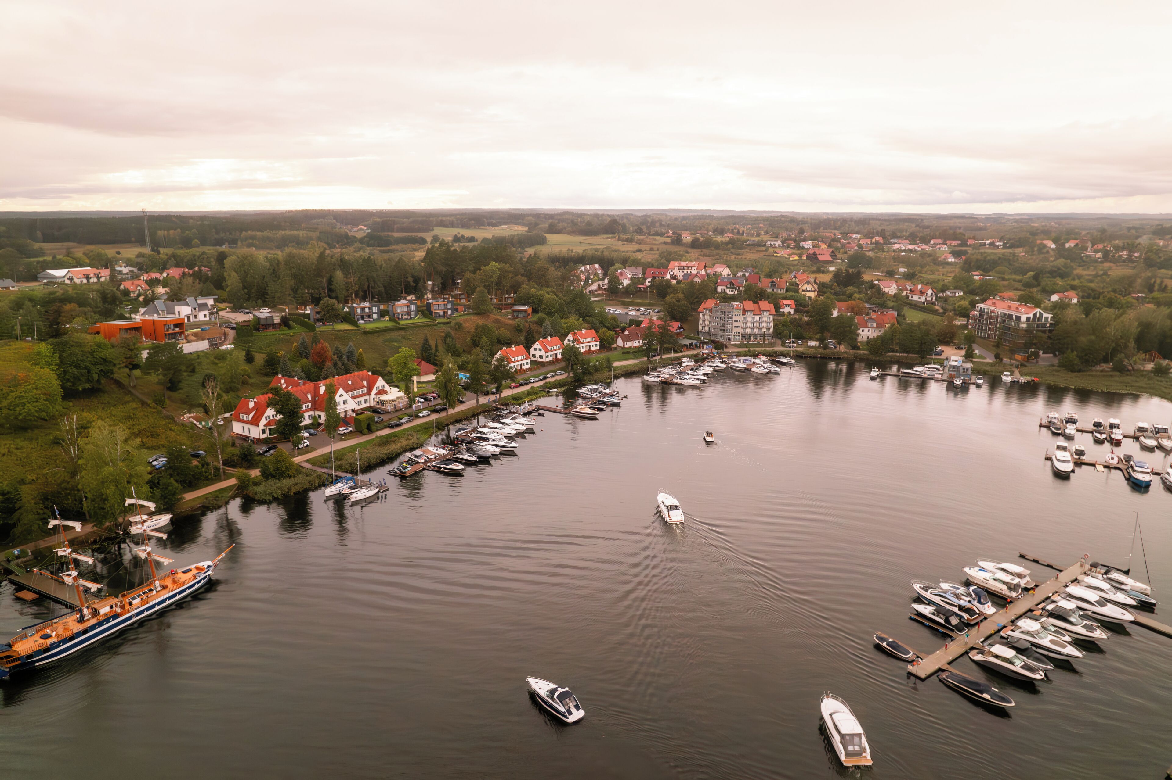 A marina with numerous boats docked, surrounded by residential buildings and greenery.