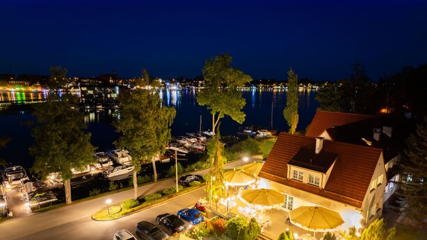A waterfront property with a covered outdoor seating area, a swimming pool, and a view of the water. - Hotel Amax (Mikolajki)
