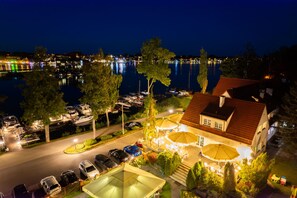 A waterfront property with a covered outdoor seating area, a swimming pool, and a view of the water. - Hotel Amax (Mikolajki)