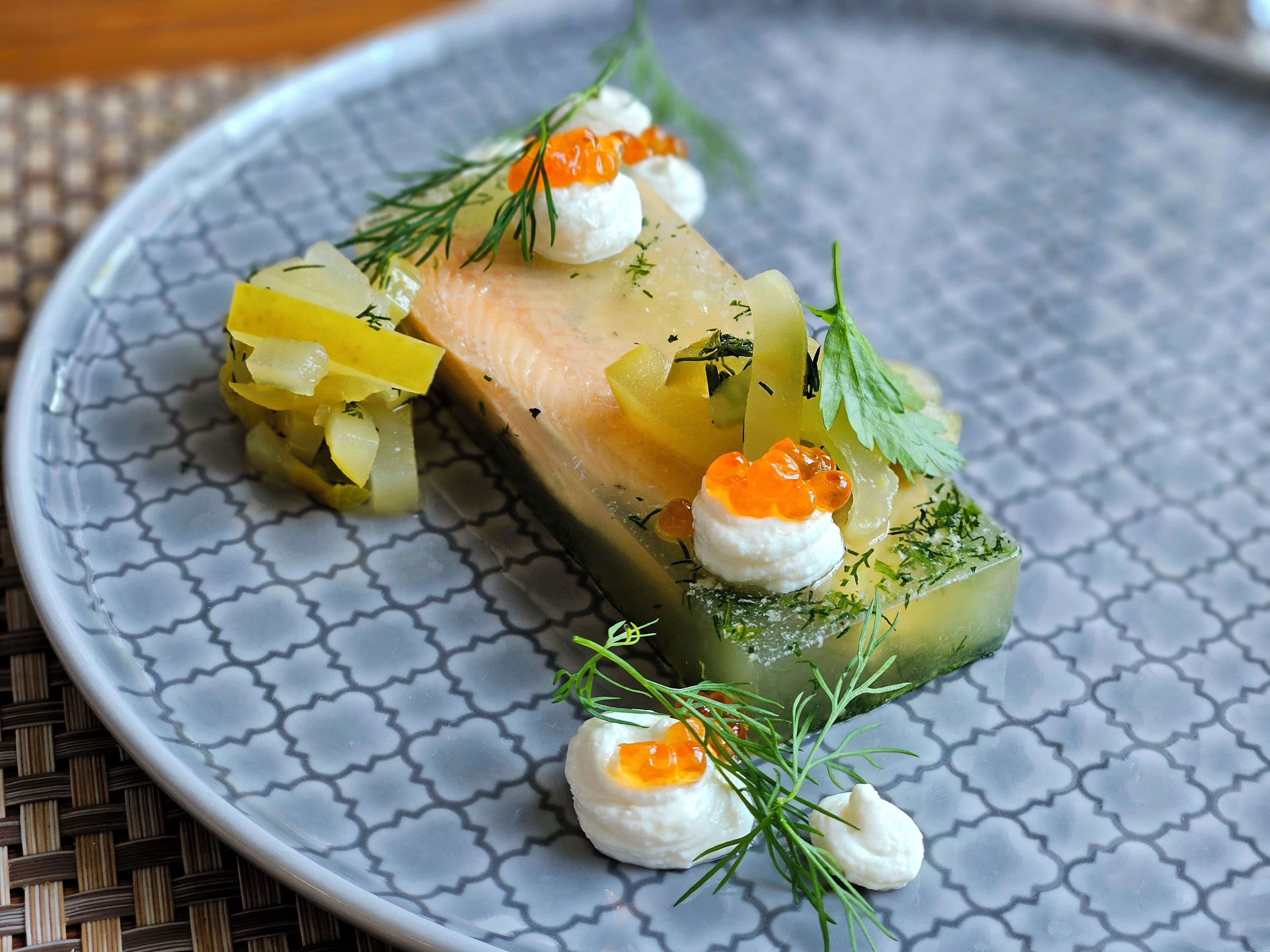 Ein Teller mit einem Lachsfilet, eingelegten Gemüsesorten und Linsen, garniert mit Dill.
