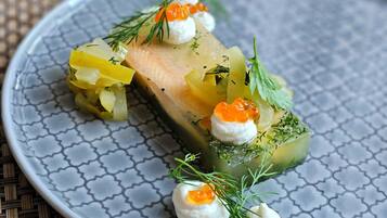 A plate with a salmon fillet, pickled vegetables, and roe garnished with dill.