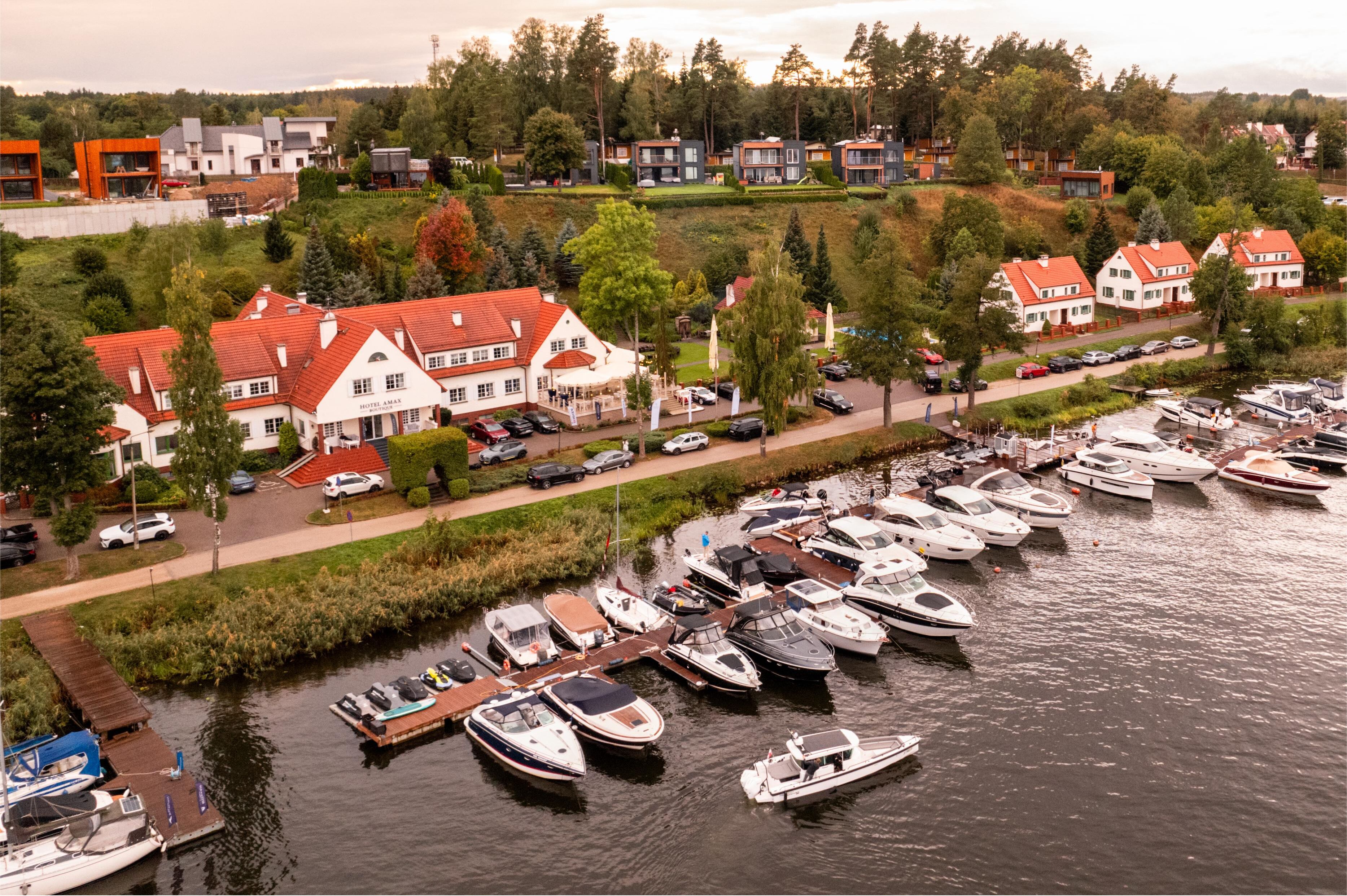A marina with boats docked, surrounded by residential buildings with red roofs and white walls.