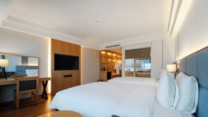Una habitación de hotel con una cama grande, un escritorio con silla, televisión y armario.