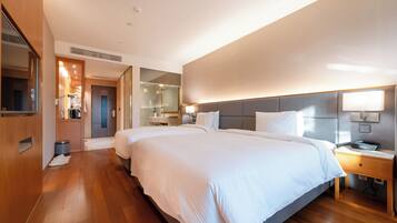 A modern hotel room with a large bed, bedside tables, a mirror, and a wardrobe.