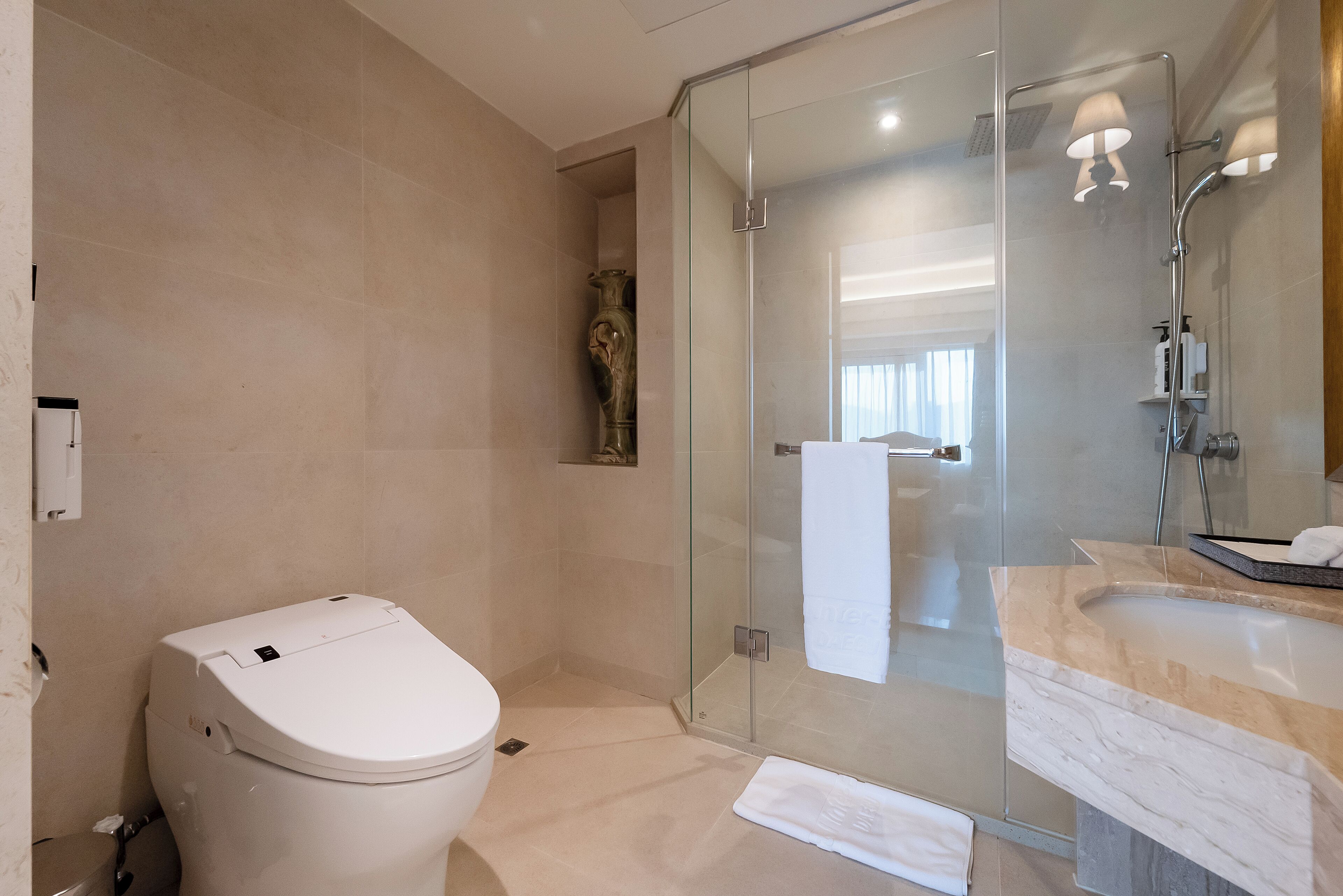 A modern bathroom with a glass shower enclosure, a white toilet, and a marble sink.
