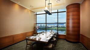 A conference room with a large table set for a meeting, large windows with a city view, and a modern ceiling design.