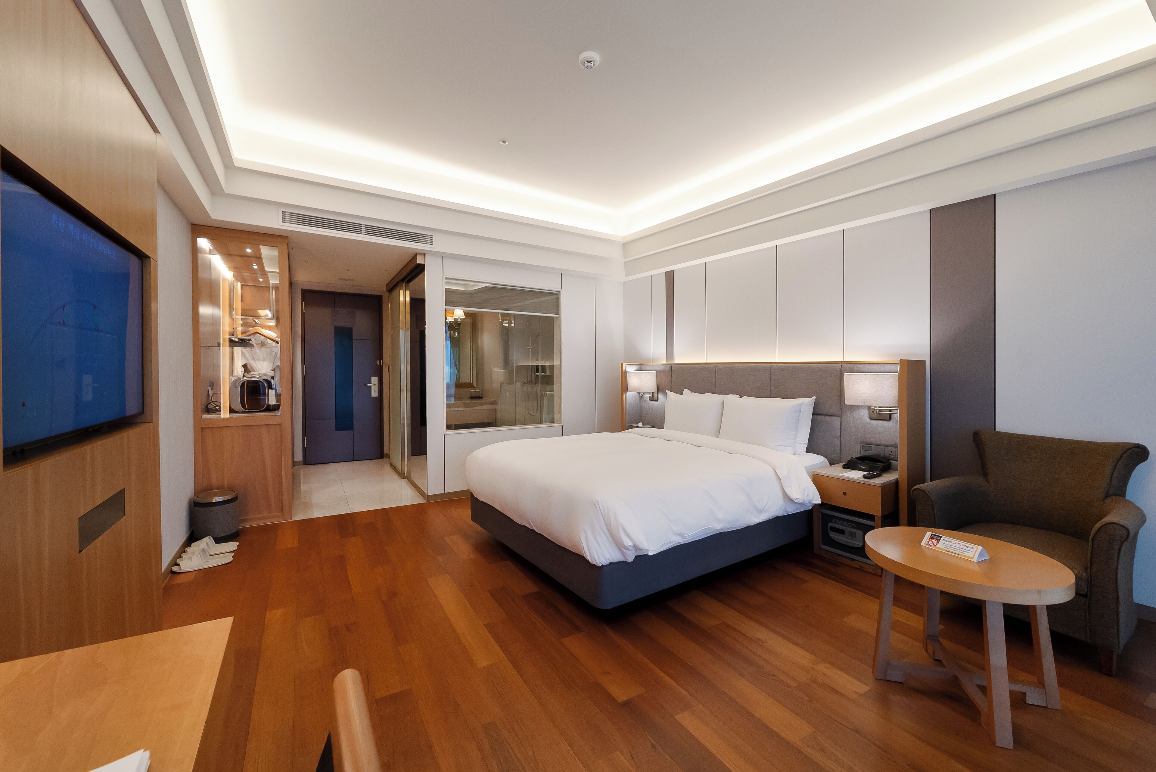 Una habitación de hotel moderna con una cama grande, un escritorio, una silla y un televisor.