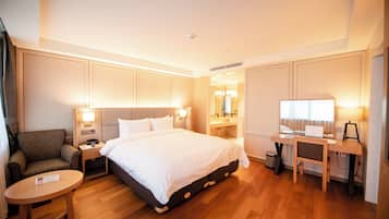 Una habitación de hotel con una cama grande, un escritorio, una silla, una mesita de noche y un espejo.
