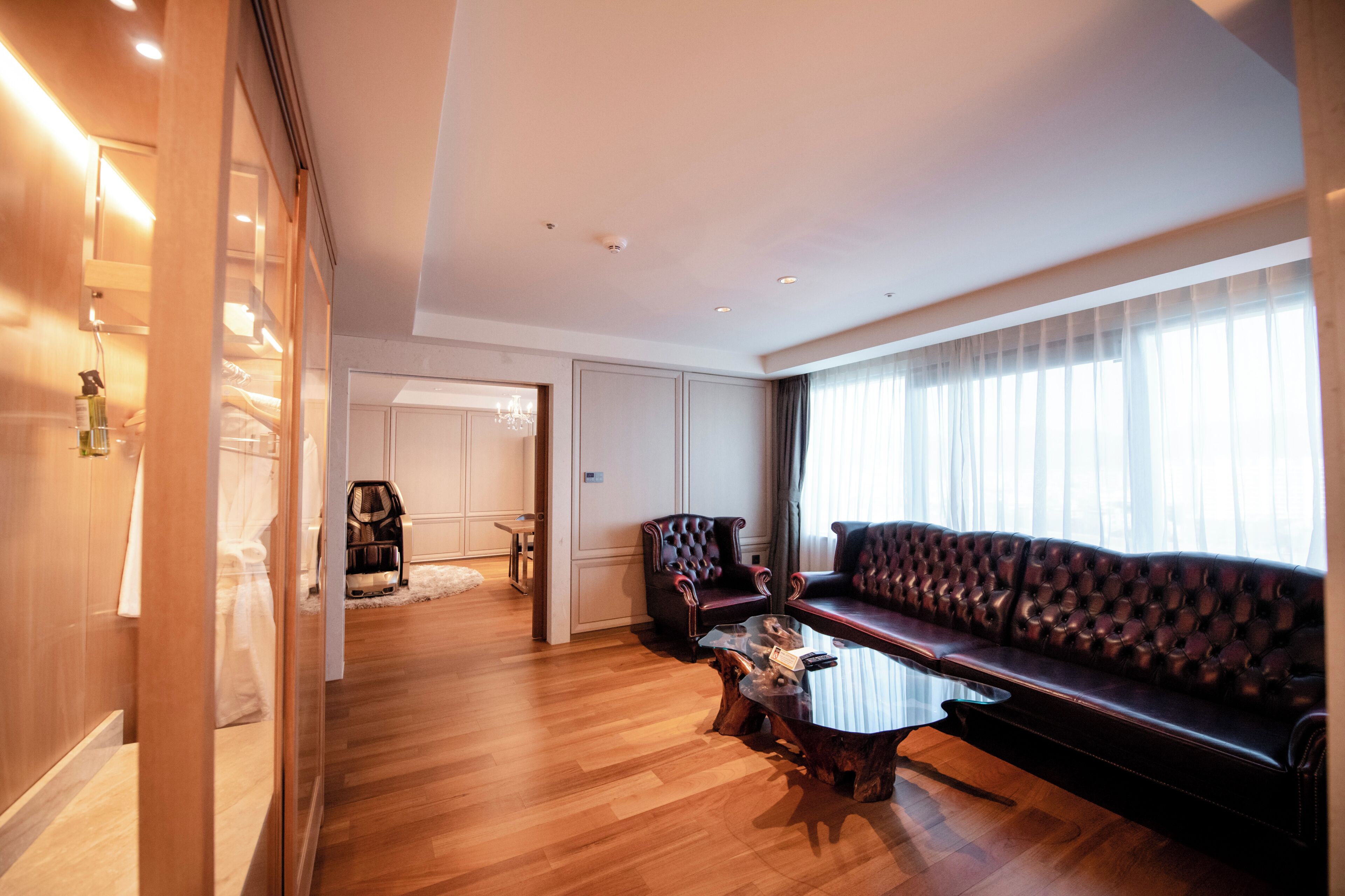 A spacious living room with a leather sofa, a glass coffee table, and a wooden floor.
