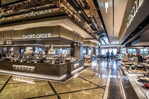 A modern food court with a 'SHORT-ORDER' counter, polished marble floors, and a high ceiling with exposed ductwork.