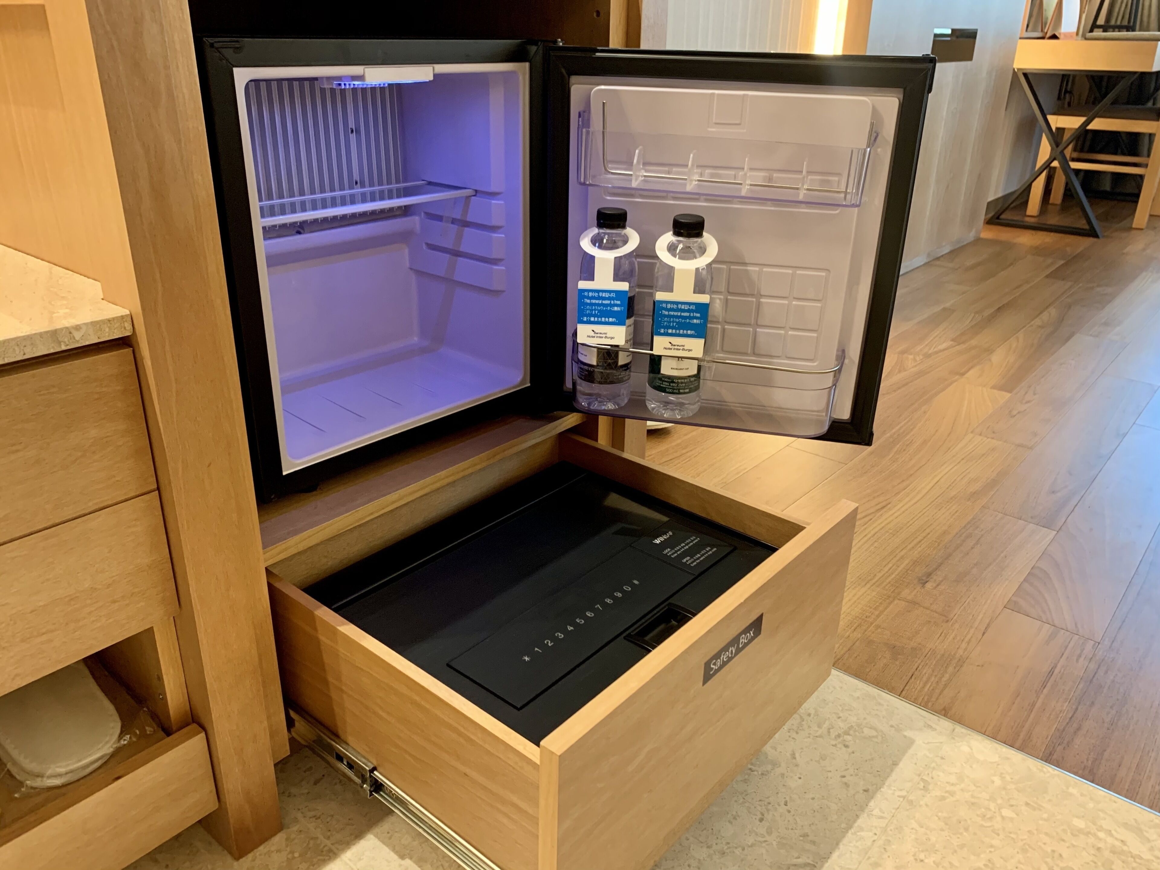 A compact refrigerator with a freezer compartment, a built-in water dispenser, and a small drawer with a black control panel.